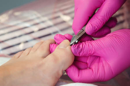 Pedicure master cuts toenails during pedicure procedure. Professional pedicure in the beauty salon. The beautician cuts the skin with fingernails and performs professional pedicure.の写真素材