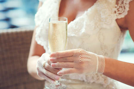 Elegant sexy woman with a glass of champagne. Summer retro party. Woman wearing white vintage dress and gloves.の写真素材