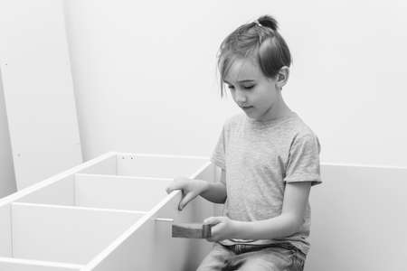 Son helping his dad to assembling new furniture at home. furniture assembly yourself. Childhood, lifestyle concept. Cute kid assembles a bookshelf himself.の写真素材