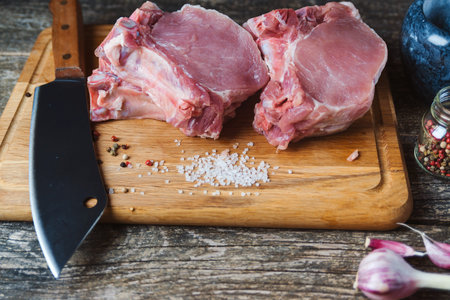 Raw fresh meat steak and meat cleaver on dark background. butcher shop. Butcher meat chopping knife...