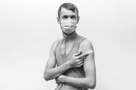 Man getting covid vaccinated. Person wearing face mask. Happy man showing his arm with bandage after receiving vaccine. Vaccination, immunization, inoculation and Coronavirus pandemic.の写真素材