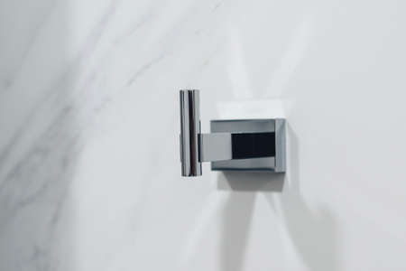 Metal hanger for towel and clothes in the bathroom. Metal hook on tiled wall. Towel hanger, close up.の写真素材