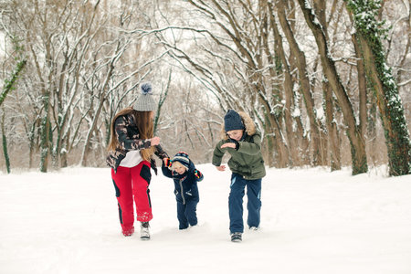 Mother with children having fun on a walk in winter park. Snowy winter weather. Happy christmas...