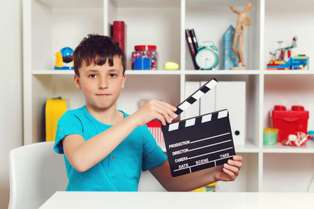 School boy holding black film making clapperboard. Producer making film. New idea for school...