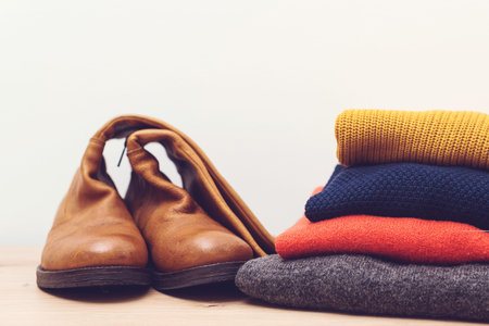 Stack of knitted warm clothes and high leather boots. Autumn, winter season women fashion. Woolen...