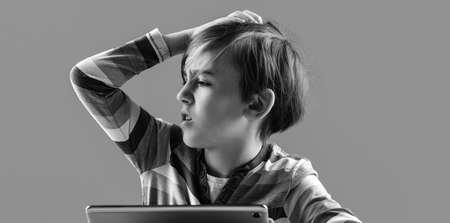 Student has headache during online lessons. Nervous kid studying online with laptop. Negative emotion during online learning or gaming at home. Unhappy boy having problem with device.の写真素材