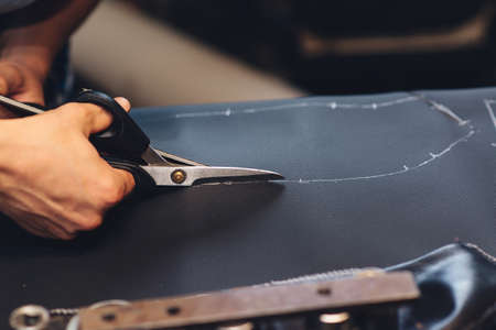 Handmade leather craftsman. Worker sewing leather product. Leather worker workshop. Working process of sewing car seat cover. Man holding crafting tool and working, close up. Making things handmade.の写真素材