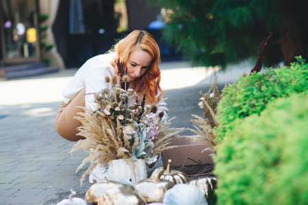 Decorator making luxury autumn holiday decoration. Woman interior designer compose dry flowers and golden pumpkins for house decor. Gold painted pumpkins and flowers for thanksgiving composition.の写真素材