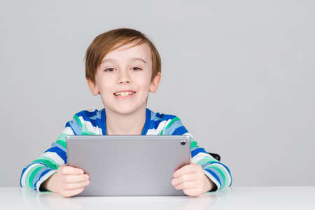 Happy boy with tablet for online lesson. Smiling cute kid using digital tablet. Online school, modern technology. Schoolboy learning at home. Children, technology and education concept.の写真素材