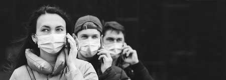 Group of young volunteers wearing face masks with mobile phones. Volunteers are ready to help. call to volunteers. The concept of mutual assistance and support. world coronavirus pandemic.の写真素材