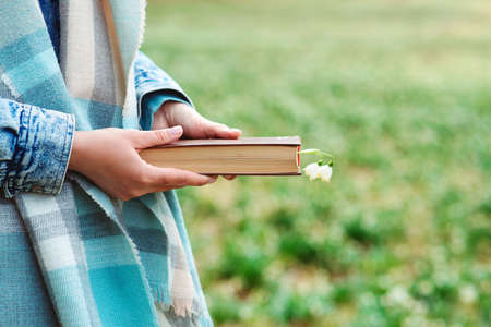 Woman with book over nature background. Reading book concept. Free space for your mockup. book in woman hands. Time for reading.の写真素材