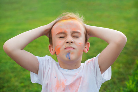 Cute boy painted in the colors of Holi festival. Happy childhood. Pre teen boy playing with colorful powder. Concept for Indian festival Holi. Holi celebrations.の写真素材