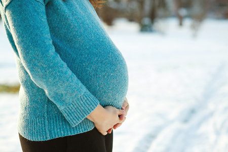 Pregnancy time. baby expectation. Pregnant woman's belly over winter background. Pregnant woman in blue sweater touching big belly with hands. Warm clothes in cold weather.の写真素材
