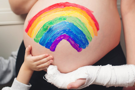 Children's hands on the pregnant belly their mother. happy family expecting baby birth. Belly painting. Happy kids and pregnant mom having fun together at home.の写真素材