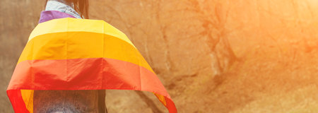 Celebrating the lgbt lesbian women rights. Woman holding the rainbow flag on the nature. Happiness, freedom and love concept for same sex couples. Lifestyle, people and love.の写真素材