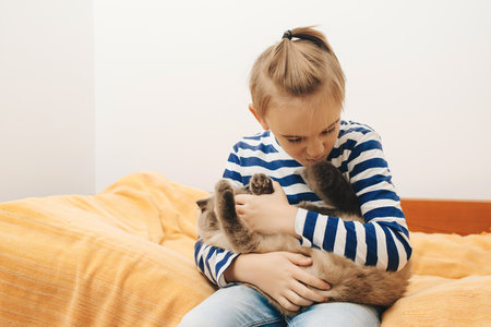 Cute boy plays with a cat at home. Happy kid hugging his cat. Boy relaxing on the bed with pet. Childhood, true friendship and home pet.の写真素材