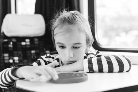Cute child playing popit toy during traveling by train. Travel by railway. Entertainment for young passengers.の写真素材
