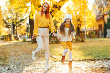 Lovely girl with her mom having fun on the walk. Autumn holidays, lifestyle. Happy family enjoying autumn weather in the park.の写真素材