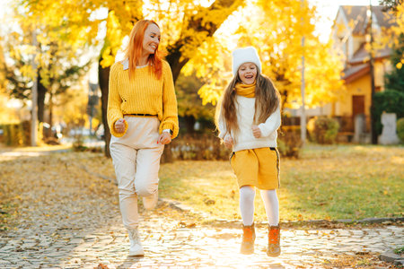 Lovely girl with her mom having fun on the walk. Autumn holidays, lifestyle. Happy family enjoying autumn weather in the park.の写真素材