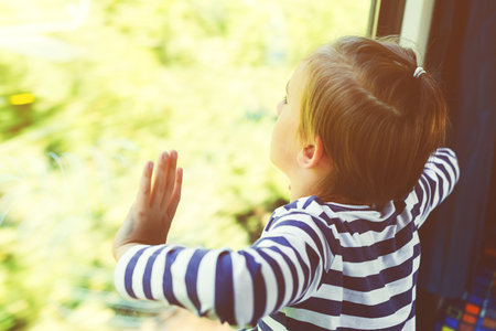 Sad child looking out the train window. Kid travels on a train. Little boy is traveling on the train. Childhood, sadness and loneliness.の写真素材