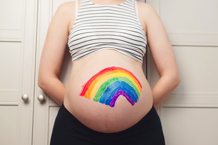 Belly painting, rainbow. Pregnant woman holding belly with painting. Waiting for baby concept. Belly painting and maternity photo.の写真素材