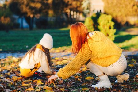 Lovely family laughing on autumn walk. Autumn holidays, lifestyle. Happy little girl and her mother playing in the autumn park.の写真素材