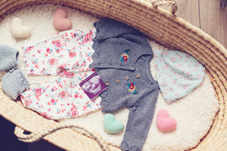 Basket with baby clothes. Wicker basket with baby stuff and accessories for newborn.の写真素材