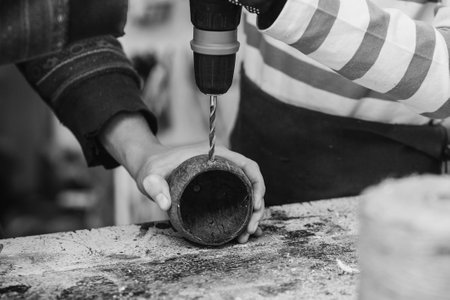 Creative student doing his project in workshop. Boy in the workshop makes crafts with coconut. School, development and learning concept. Young carpenter working in craft workshop.の写真素材