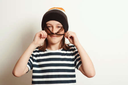 Excited boy having fun and posing at studio. Portrait of eleven years old boy. Boy wearing stylish woolen hat and tshirt. Lifestyle, people, emotion concept.の写真素材