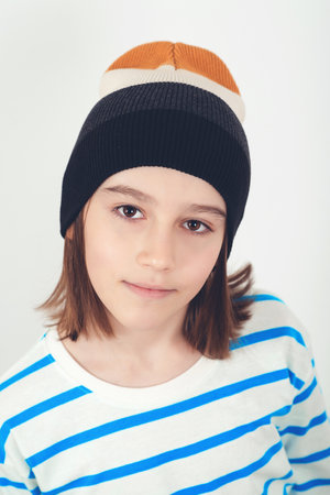 Cute boy wearing stylish woolen hat. Kid posing over on white background. Face portrait of eleven years old kid.の写真素材