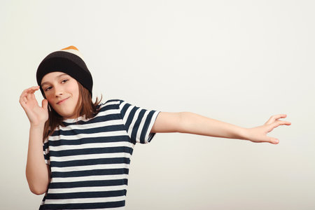 Excited boy having fun and posing at studio. Portrait of eleven years old boy. Boy wearing stylish woolen hat and tshirt. Lifestyle, people, emotion concept.の写真素材