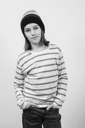 Stylish confident boy smiling over white background. Cute guy wearing woolen hat. Portrait of eleven years old boy. Lifestyle, fashion and people.の写真素材