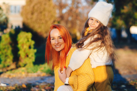 Lovely family laughing on autumn walk. Autumn holidays, lifestyle. Happy little girl and her mother playing in the autumn park.の写真素材
