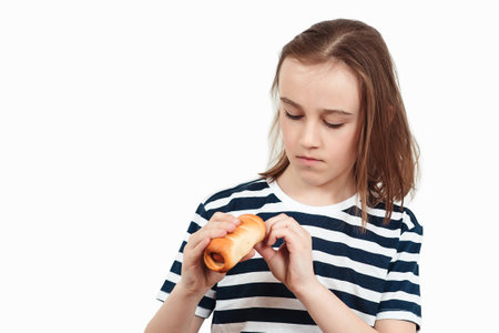 Happy boy holding tasty bun with sausage. Hungry boy eating snack. Childhood, unhealthy food.の写真素材