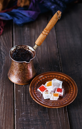 Turkish coffee and Turkish Delight over dark wooden background. Selective focus, Shallow DoF, dramatic lighting, vintageの写真素材