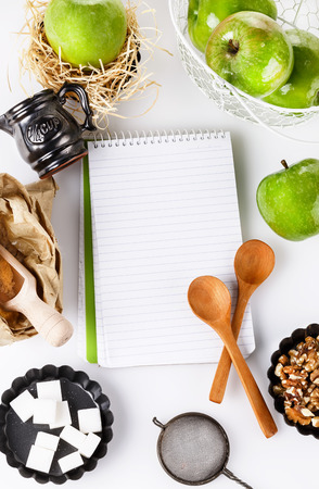 Recipe book and ingredients for baking apple pastry over white background.の写真素材