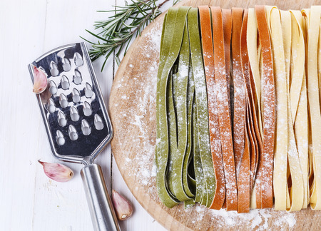 Colorful fettuccine dusted with flour over rustic wooden background. Top viewの写真素材