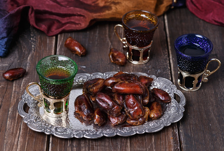 Ramadan date palm on a silver plate and tea over wooden backgroundの写真素材