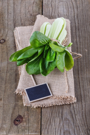 Bunch of bock (pack) choy cabbage with tag over rustic wooden backgroundの写真素材