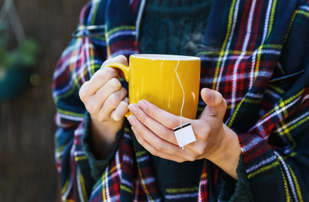 Female in warm clothing holding cup of hot tea. Selective focus, shallow Depth of Fieldの写真素材