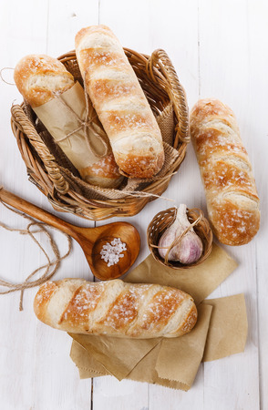 Stone Baked Pane Di Casa bread rolls, garlic and salt on a white wooden backgroundの写真素材