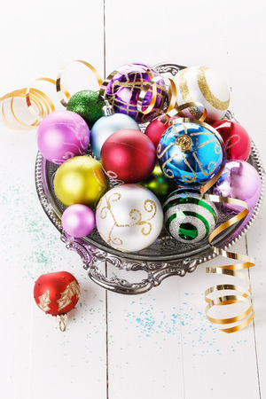 Colorful Christmas ornaments on a plate over white wooden backgroundの写真素材