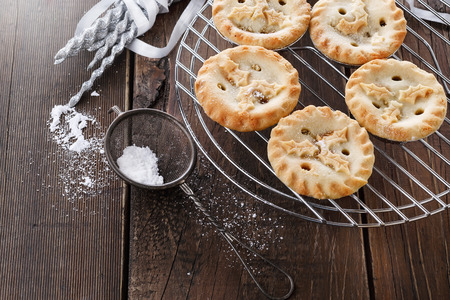 Christmas fruit mince pies on a cooling rack over rustic wooden backgroundの写真素材