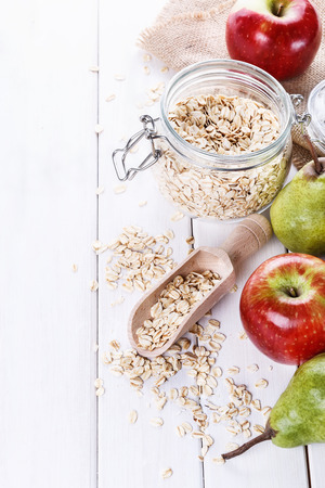 Fresh apples and pears and rolled oats over white wooden background with copyspace. Selective focus, shallow DoFの写真素材