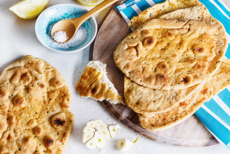 Freshly baked spicy flat bread, garlic and salt on a kitchen counter surface