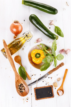Food concept:  green and yellow organic vegetables, aromatic oil, herbs and spices over white wooden background. Top viewの写真素材