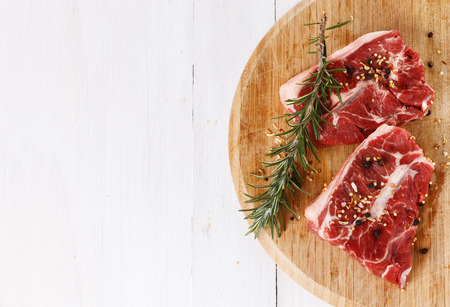 Red meat and rosemary over white wooden background with copy space. Top viewの写真素材