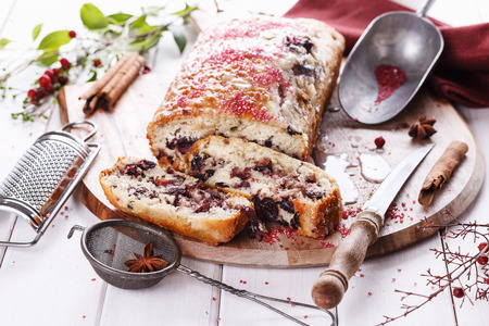 Freshly baked cranberry loaf and slices on a cutting board over white wooden backgroundの写真素材