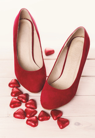 Red shoes and chocolate hearts for Valentine over white background. Vintage effect, color toningの写真素材