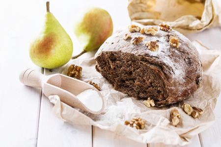 Freshly baked rye sourdough with walnuts and pears on wooden backgroundの写真素材